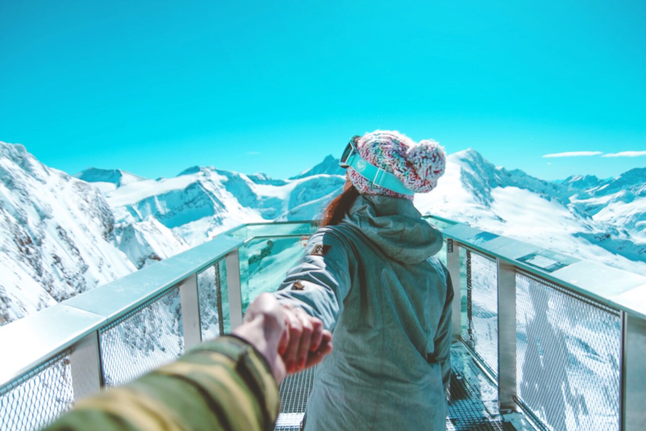 a woman leading a man by his hand on a cliff